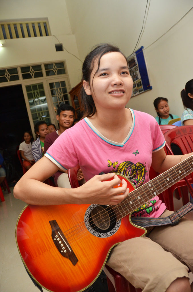 Nuori kambodzhalainen tyttö soittaa kitaraa.