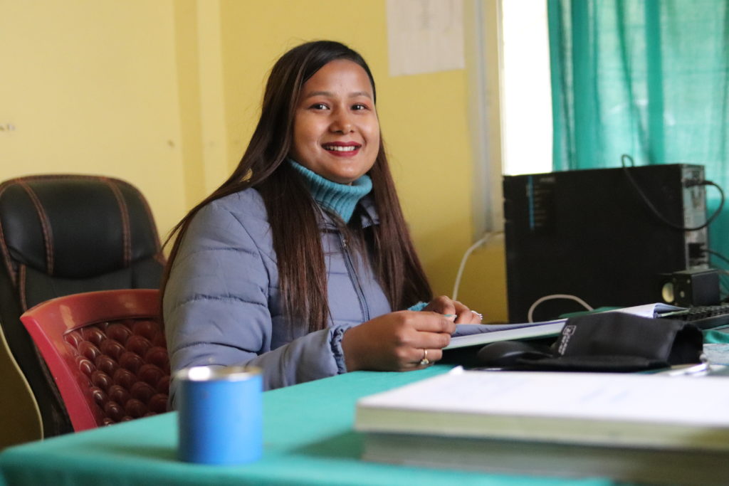 Terveydenhoitaja Jyoti Chaudhary hymyilee työpisteellään.