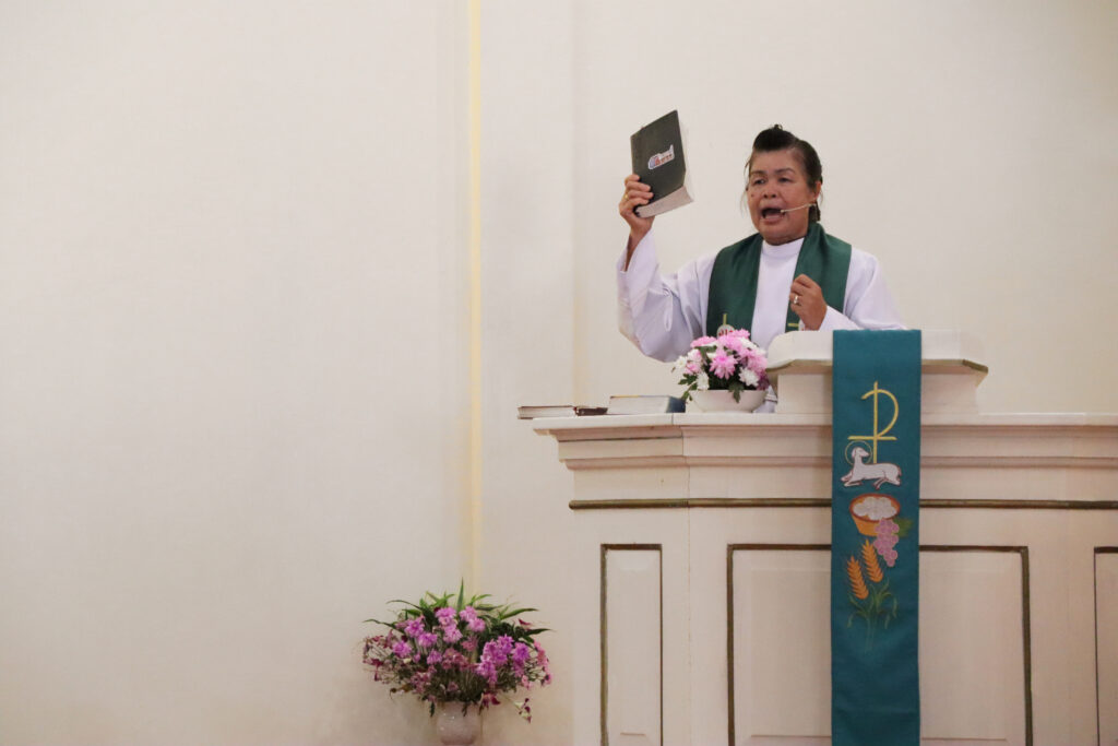 Pastori saarnaamassa jumalanpalveluksessa kädessään Raamattu.