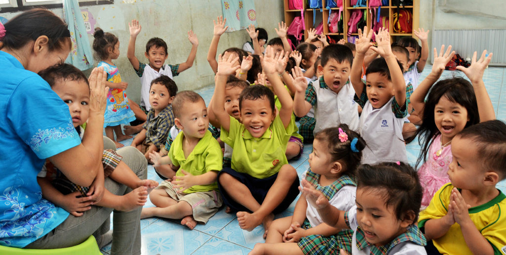 Bild på barn med händerna i luften. Barnhemmet Samrong, Bangkok.
