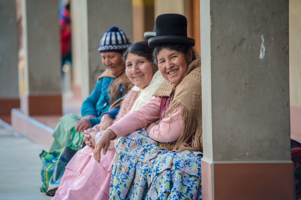 Kolme bolivialaisnaista rivissä perinteisissä alkuperäiskansojen asuissa.