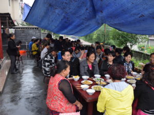 Kiinalaisia syömässä pihalle katettujen pöytien ääressä.