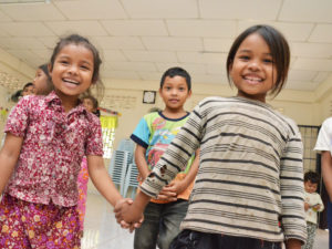 Iloisia kambodzhalaisia lapsia käsi kädessä.