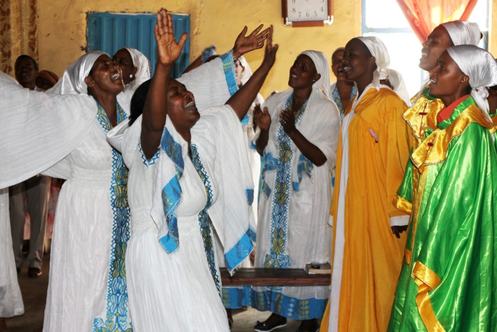 Etiopialaiset naiset tanssivat perinteisissä vaaleissa juhla-asuissa.