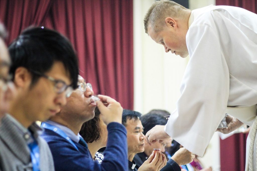 Suomalainen pappi jakaa ehtoollista taiwanilaisille luterilaisen seminaarin opiskelijoille.
