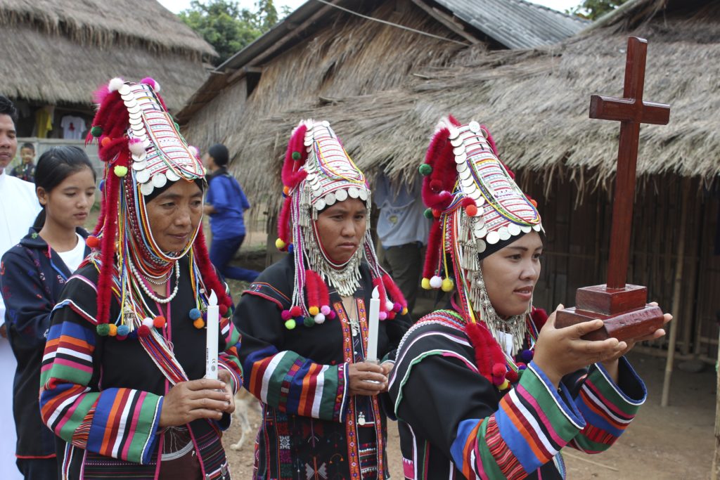 Kolme thainaista ristikulkueessa perinteisissä thaimaalaisissa asuissa.