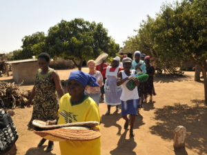 Zimbabwelaiset naiset kantavat tavaroita hymyillen.
