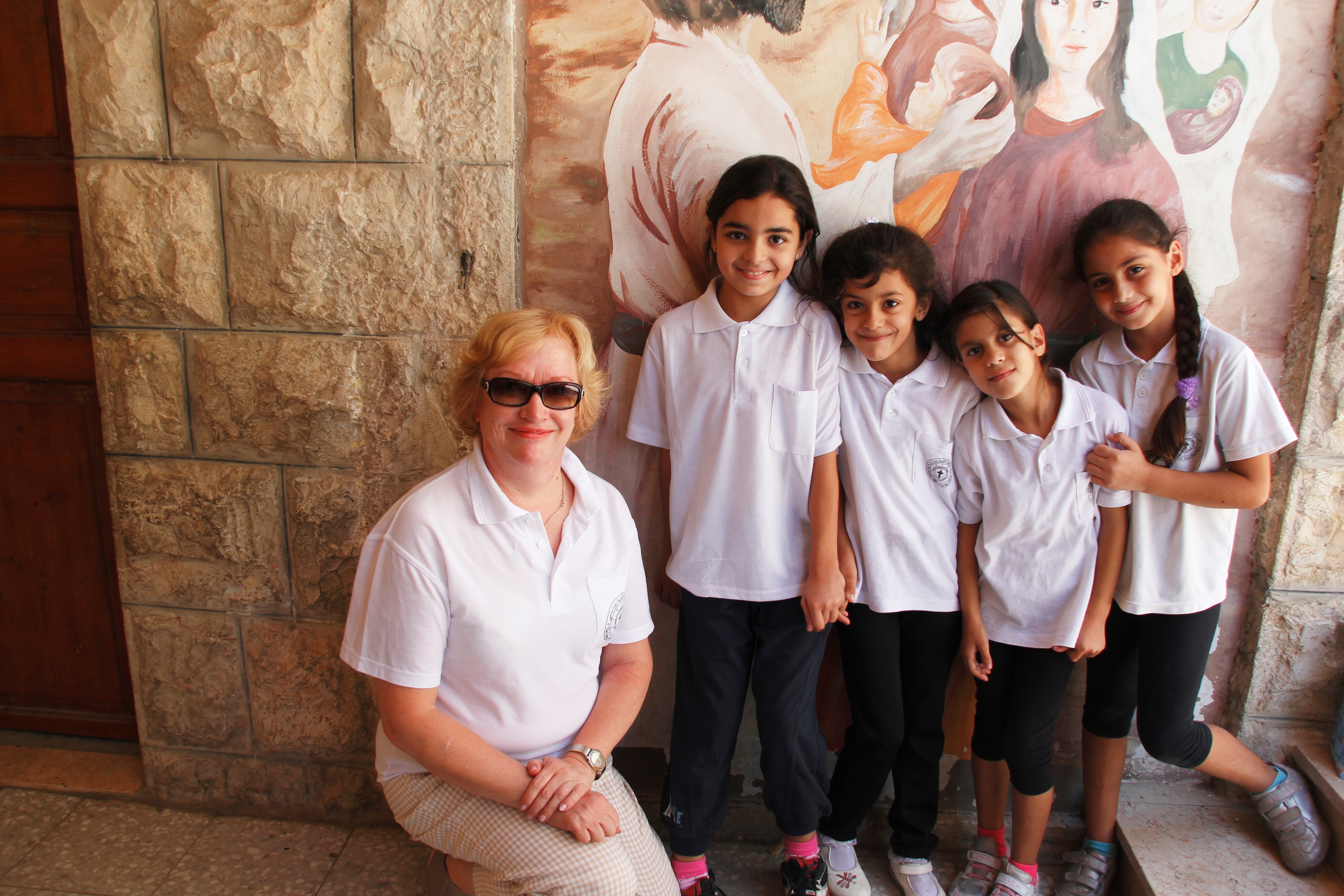 Kummiyhdyshenkilö Riitta Luume saa nopeasti seuraa välitunnilla Beit Sahourin luterilaisessa koulussa. Kummit tukevat 52 lapsen opiskelua koulussa. Kuva Marjatta Kosonen