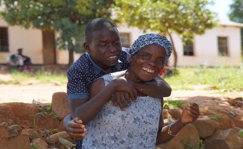 Äiti kantaa vammaista poikaansa selässään Zimbabwessa.