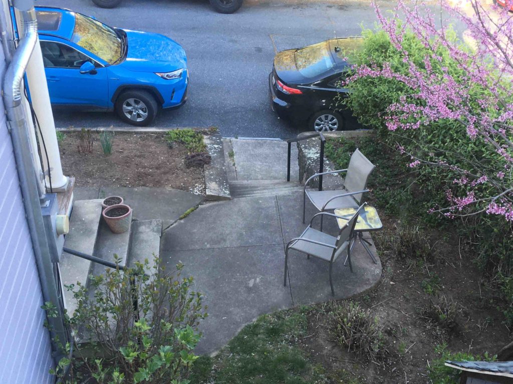 Kaksi puista puutarhatuolia seisoo portaiden edessä talon etupihalla.