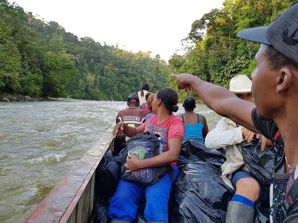Kapea jokivene täynnä ihmiisiä ajaa viidakon keskellää