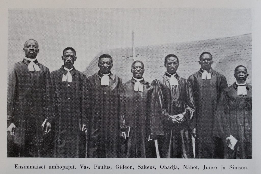 Namibialaisia pappeja rivissä liperit kaulassa.