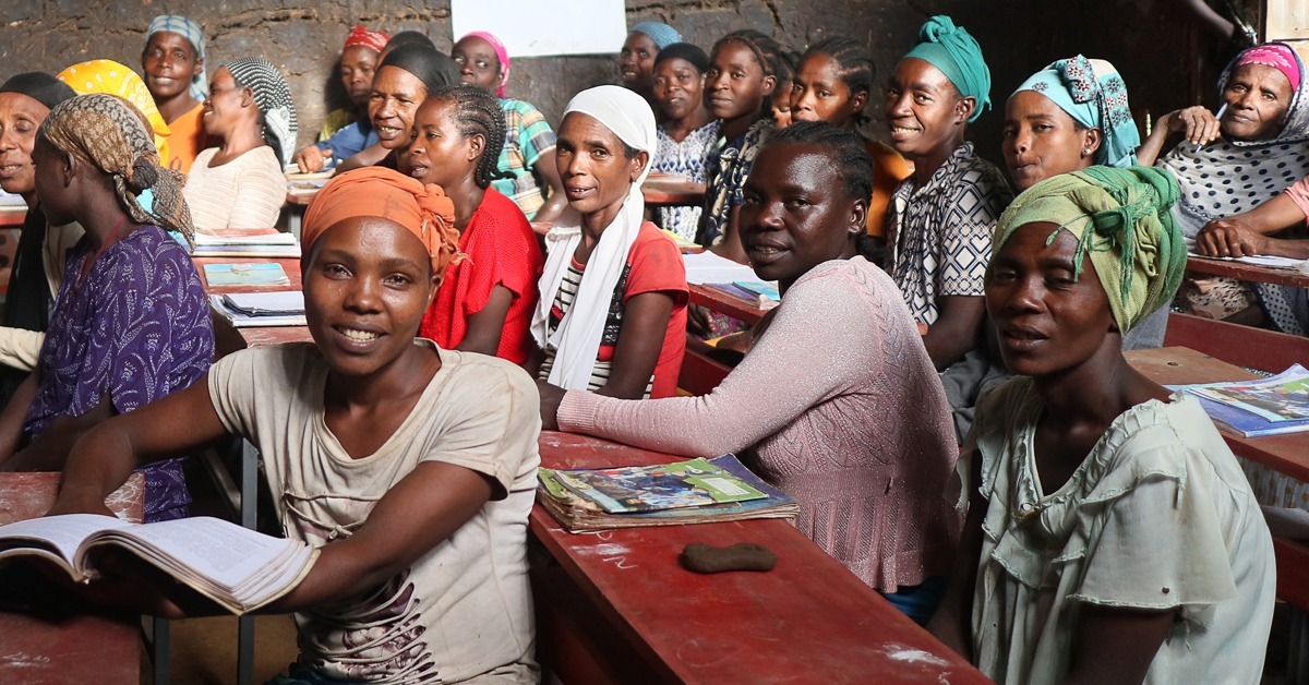 Etiopialaisia naisia istuu pulpettien takana koululuokassa.