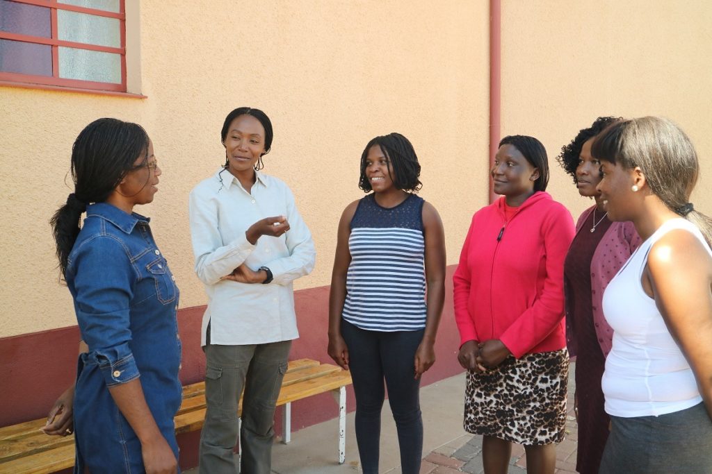 Pastori Emma Namgolo juttelee kirkon pihalla nuorten naisten kanssa.