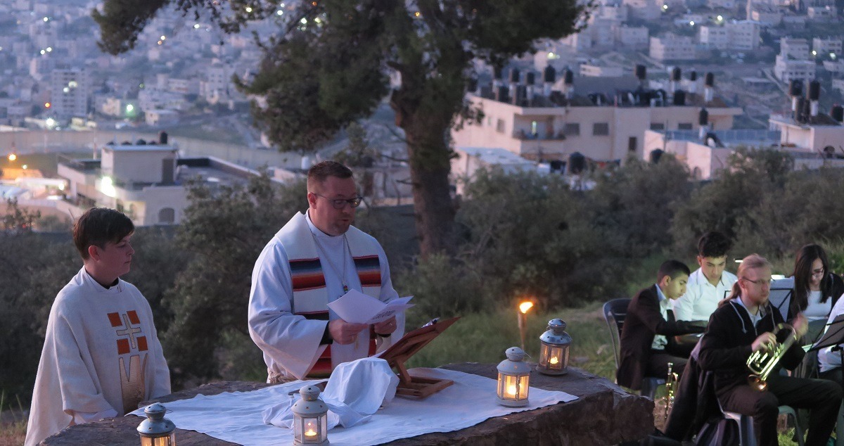 Kaksi pappia ulkona alttarilla, takana näkymä Jerusalemin kaupunkiin aamuhämärässä.