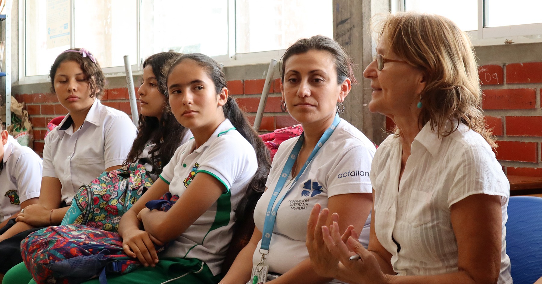 Kuvassa Arja Koskinen istuu nuorten kolumbialaisnaisten kanssa keskustelemassa.
