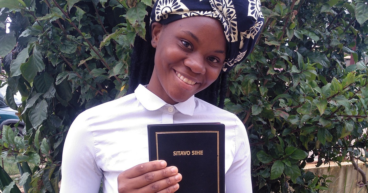Angolalainen 18-vuotias Maria pitää ilonen hymy kasvoillaan edessään songonkielistä Uutta testamenttia.