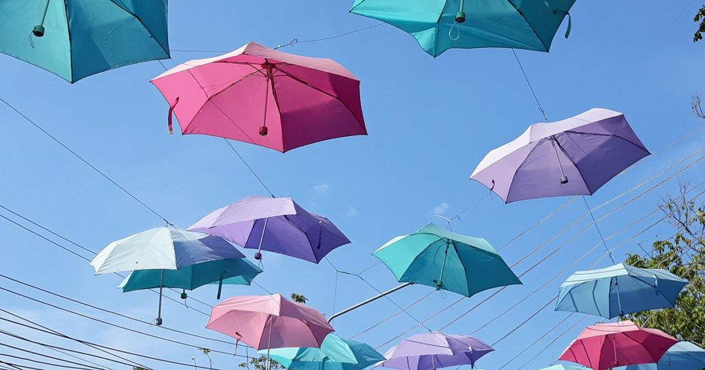 Kuvassa värikkäitä sateenvarjoja sinistä taivasta vasten.