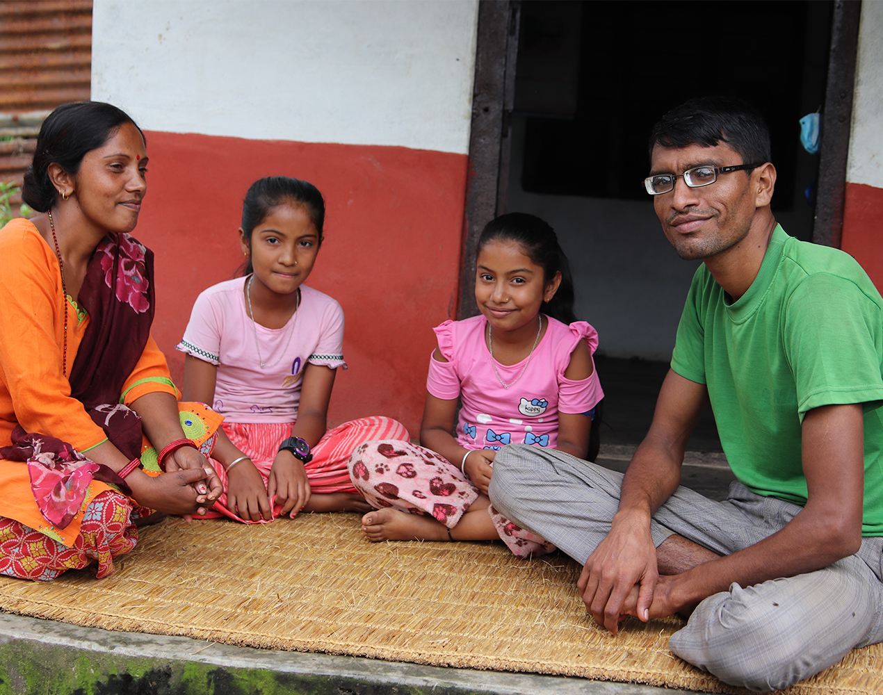 Santosh istuu matolla vaimonsa ja kahden lapsensa kanssa