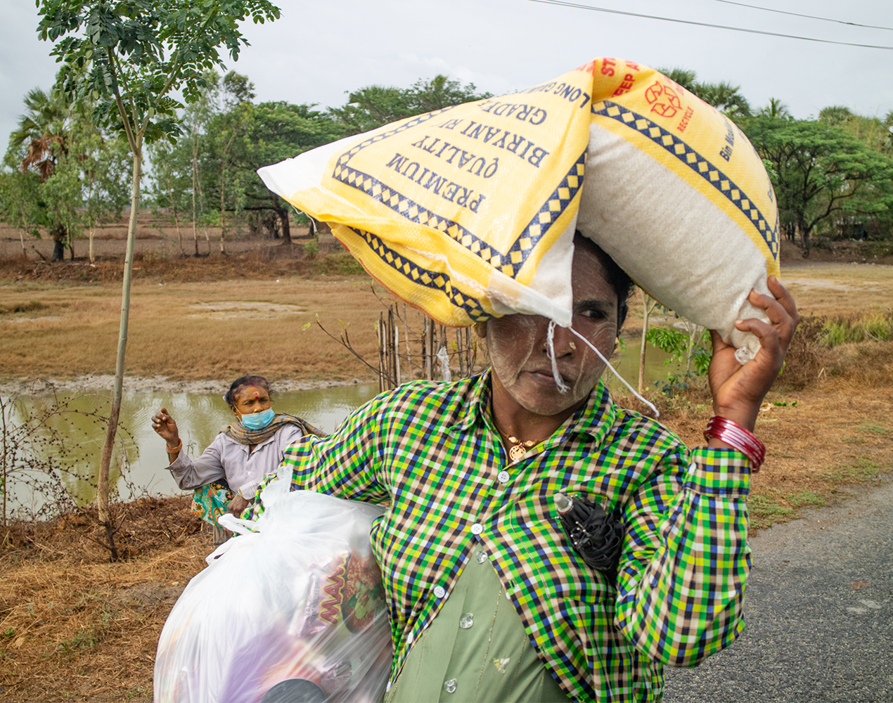 Nainen kantaa ruokasäkkiä päänsä päällä Mynmarissa