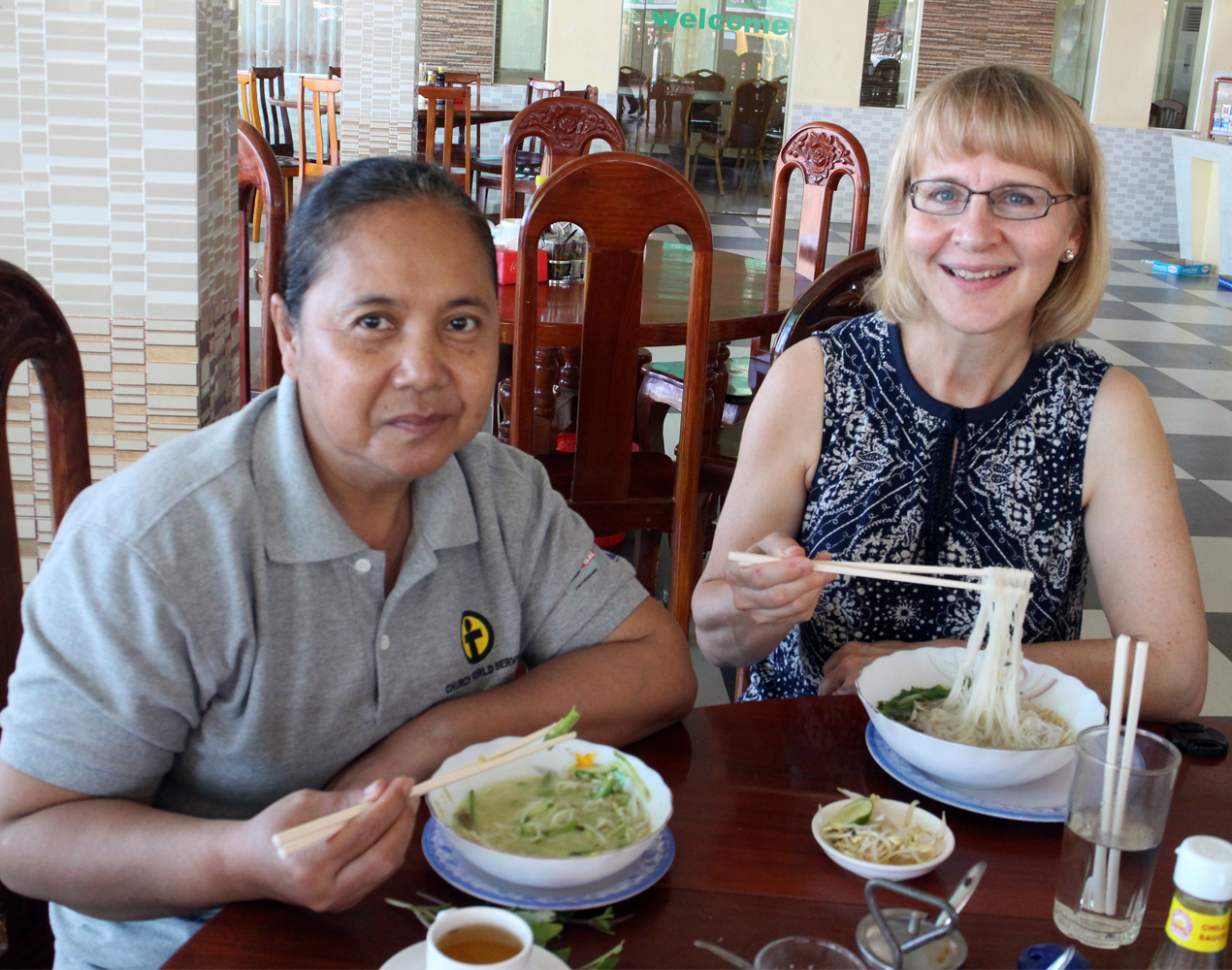 Pirre Saario ja kambodžalaisen ruokaturvahankkeen työntekijä lounaalla nuudelikulhot edessään.
