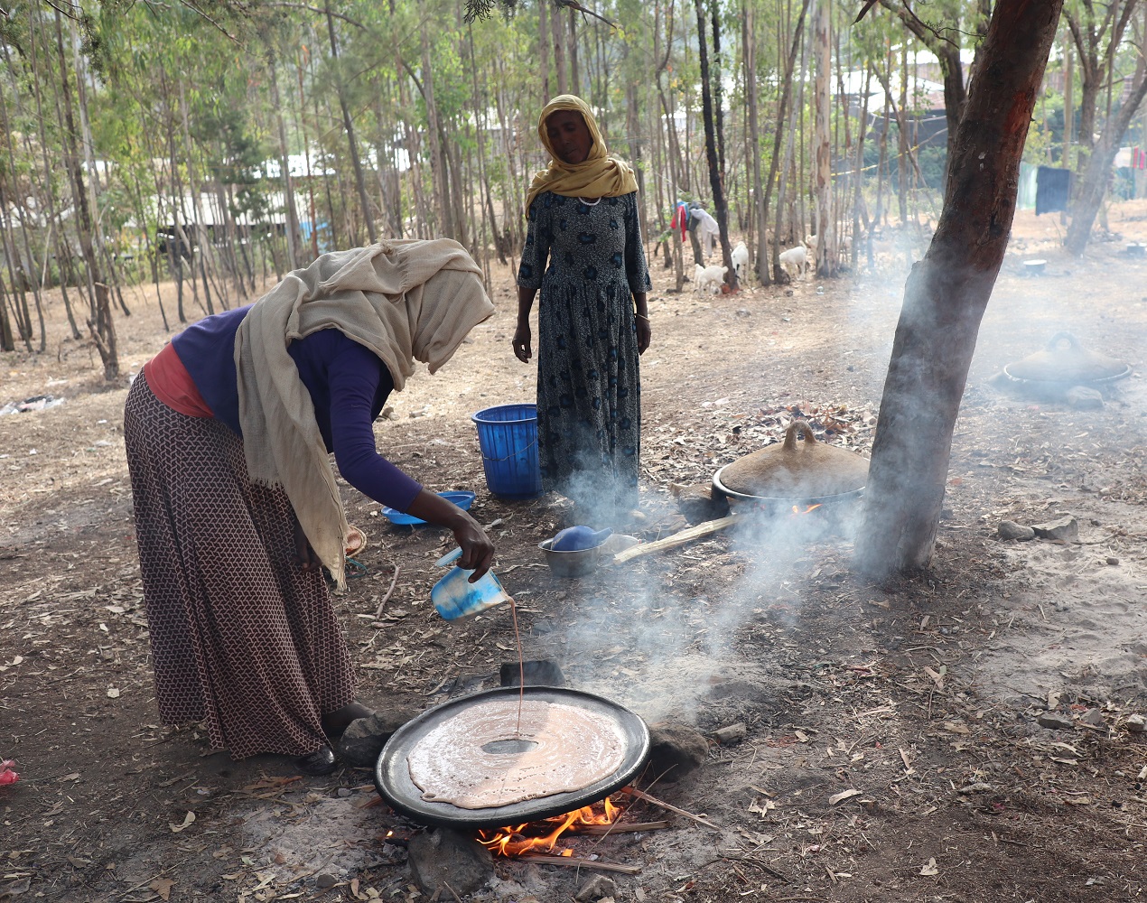Kaksi naista kokkaamassa pakolaisleirillä.