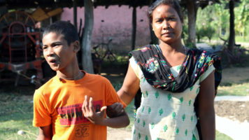 Nepalilainen nainen pitää kiinni vammaisen 15-vuotiaan poikansa käsivarresta.