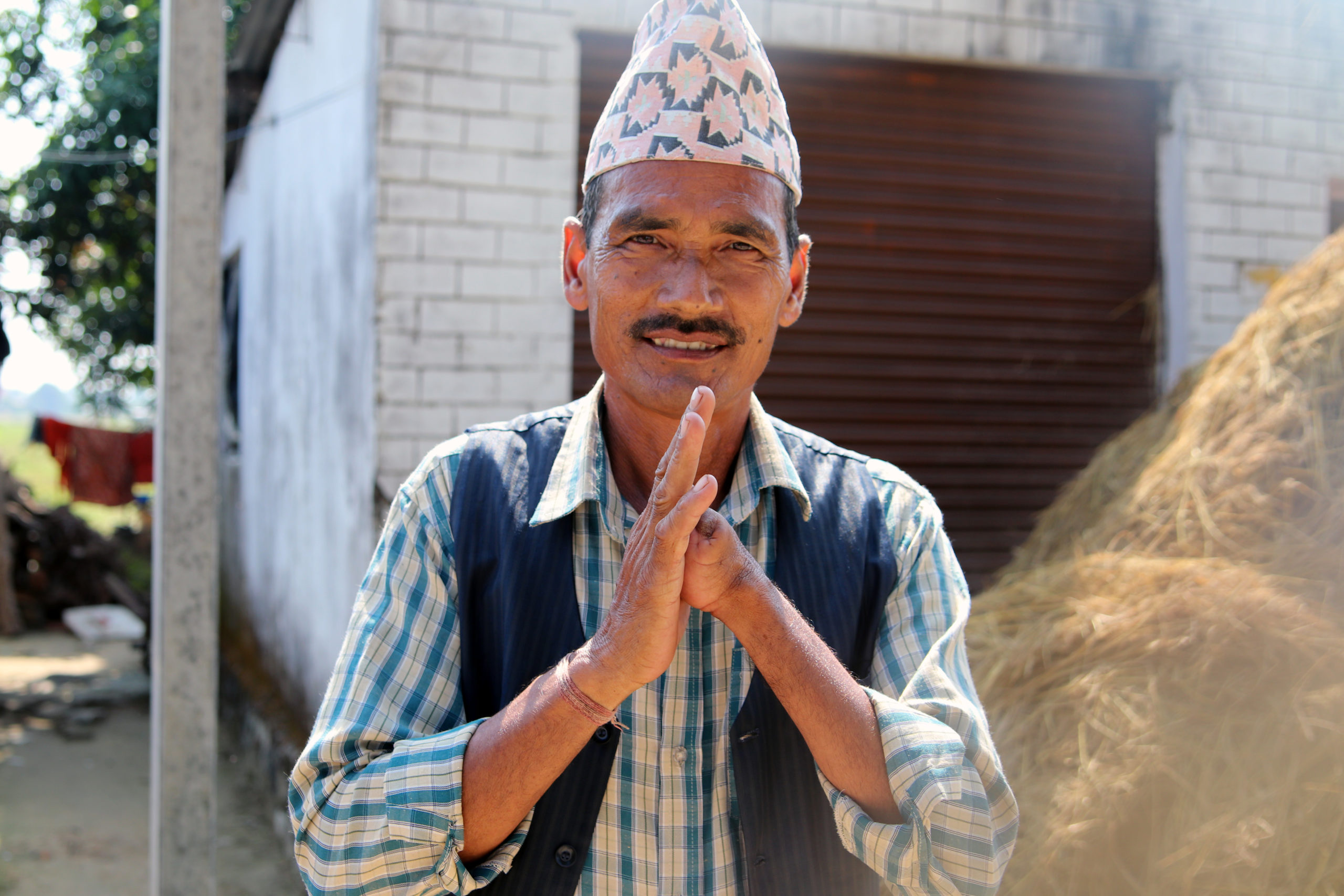 Nepalilaismies tekee hymyillen namaste-tervehdystä. Häneltä puuttuu toinen käsi.