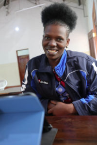Nuori tansanialainen hymyilee tabletin ääressä.