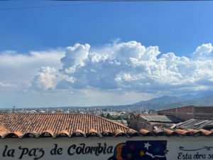 Sininen taivas punatiilikattojen yllä Medellinissä. Talon seinässä näkyy teksti La paz de Colombia.
