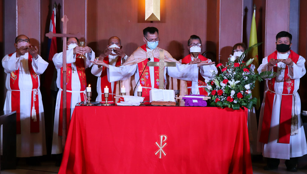 Piispa seisoo kädet sivuille levitettynä pitämässä ehtoollisliturgiaa.