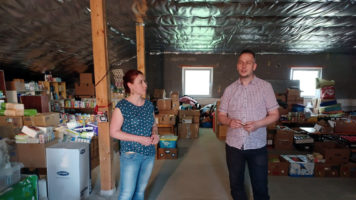 Mies ja nainen seisovat keskellä avustustarvikkeita.