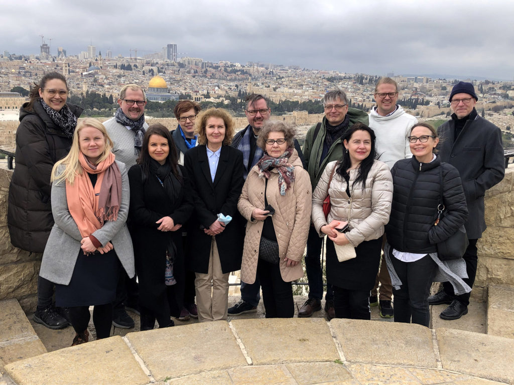 Ryhmämatkalaiset seisovat ikonisen Jerusalemin kaupunkimaiseman edessä. Taustalla näkyy mm. Temppelivuorella sijaitseva Kalliomoskeija.