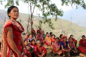 Nepalilaisia naisia istumassa ulkona, etualalla nainen puhumassa
