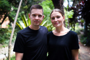 Mustiin t-paitoihin pukeutunut nainen ja mies, suomalainen aviopari, takana Kolumbian vihreää kasvustoa