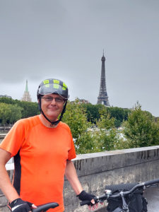 Punapaitainen mies pyöräilykypärässä, taustalla näkyy Pariisin Eiffel-torni