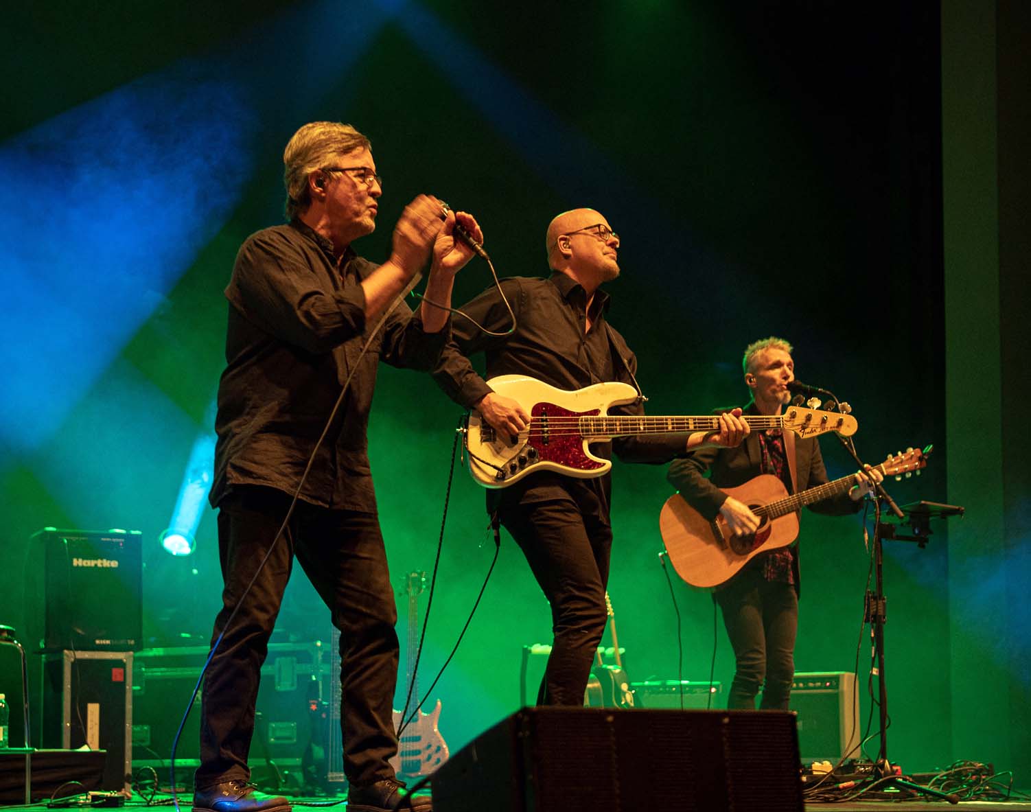 Pekka Simojoki laulaa lavalla mustissa vaatteissa, kaksi miestä soittaa kitaraa.