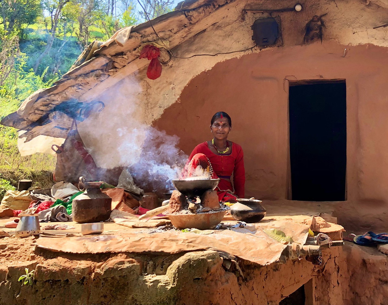 Nepalilaisnainen kokkaa mutatalon edustalla