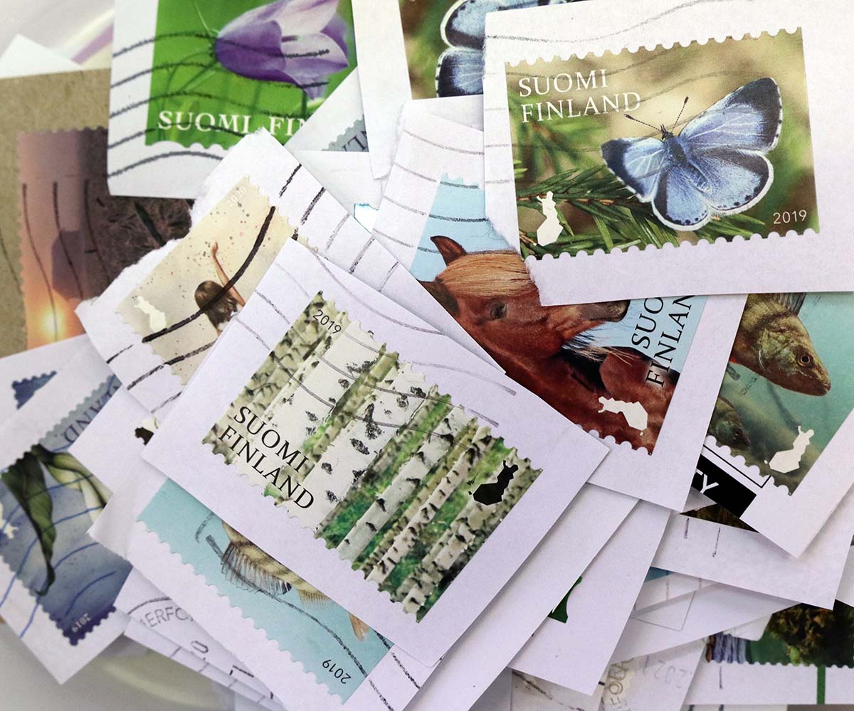 Lähikuvassa kirjeistä leikattuja suomalaisia postimerkkejä.