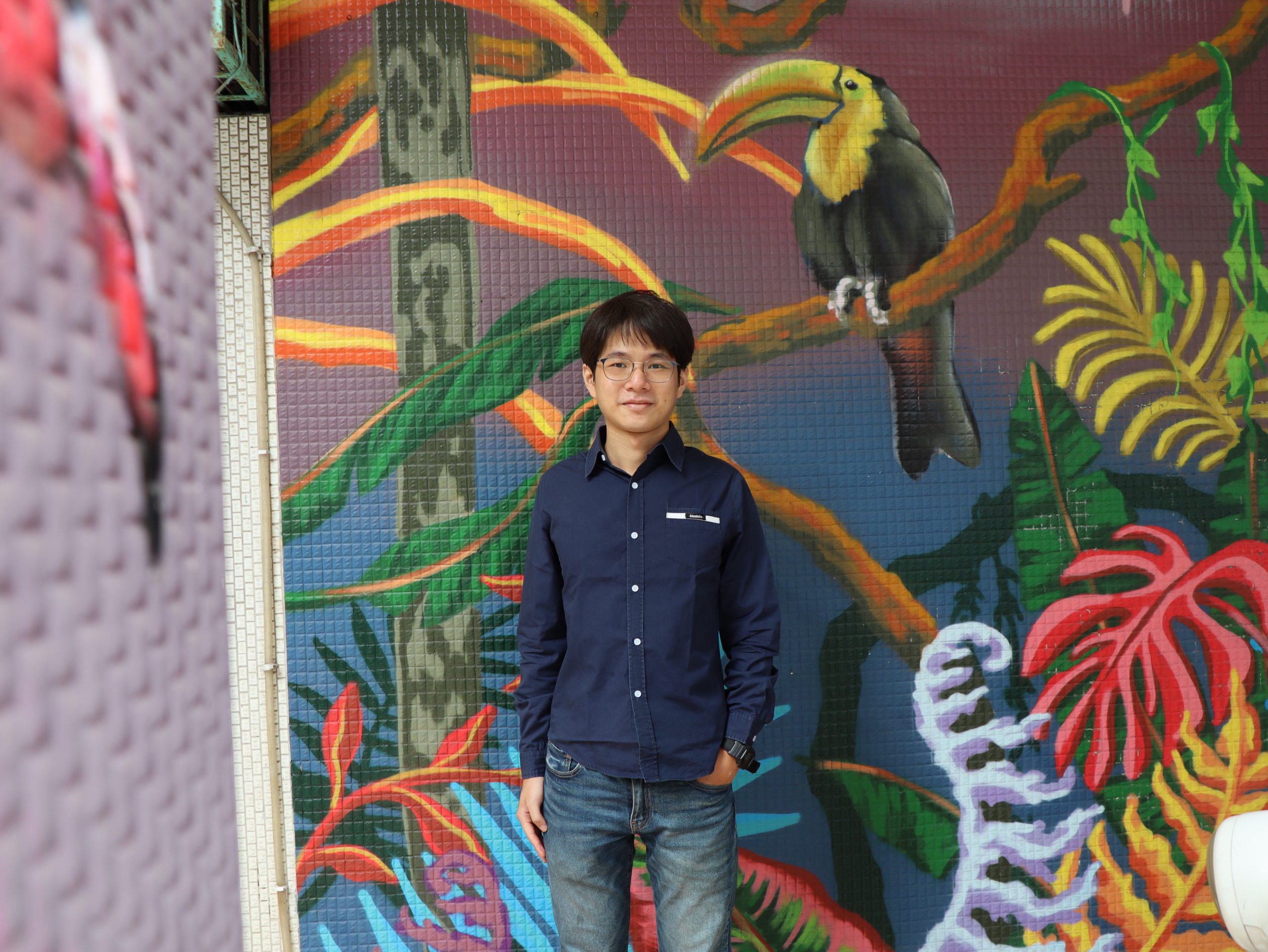 Liang Chin-Ming seisoo värikkään seinämuraalin edessä