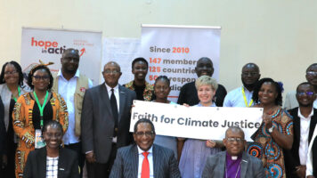 ACTin tapaamiseen osallistuneita ihmisiä ryhmäkuvassa. Keskellä Ruusa Gawaza, jolla on kädessään kyltti, jossa lukee Faith for Climate Justice.