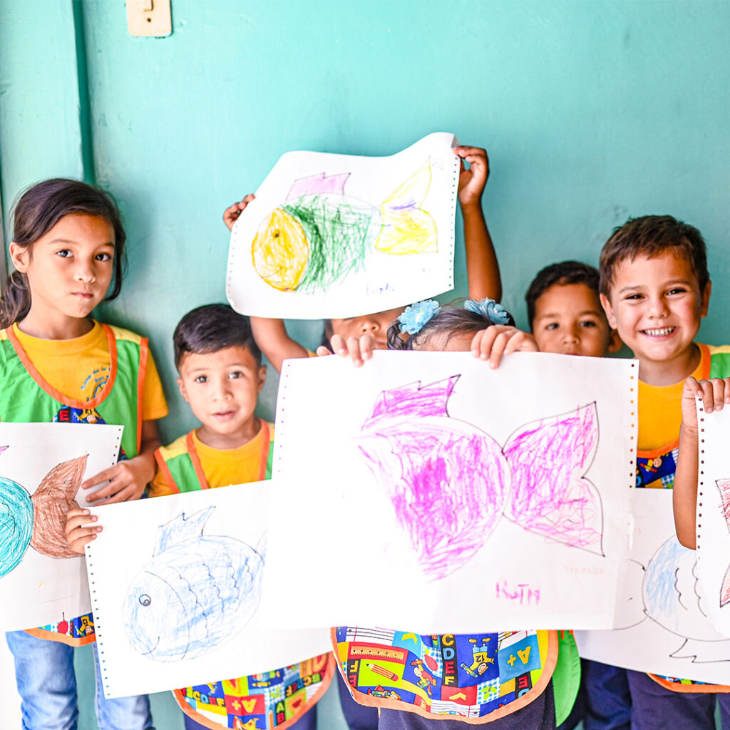 Joukko lapsia käsissään värikkäitä piirustuksia